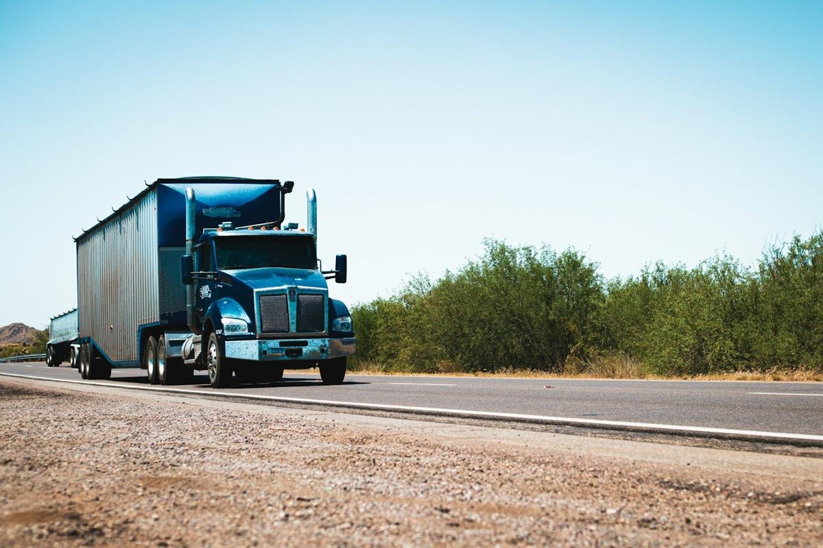 Blue tractor pulling a dry van along a highway