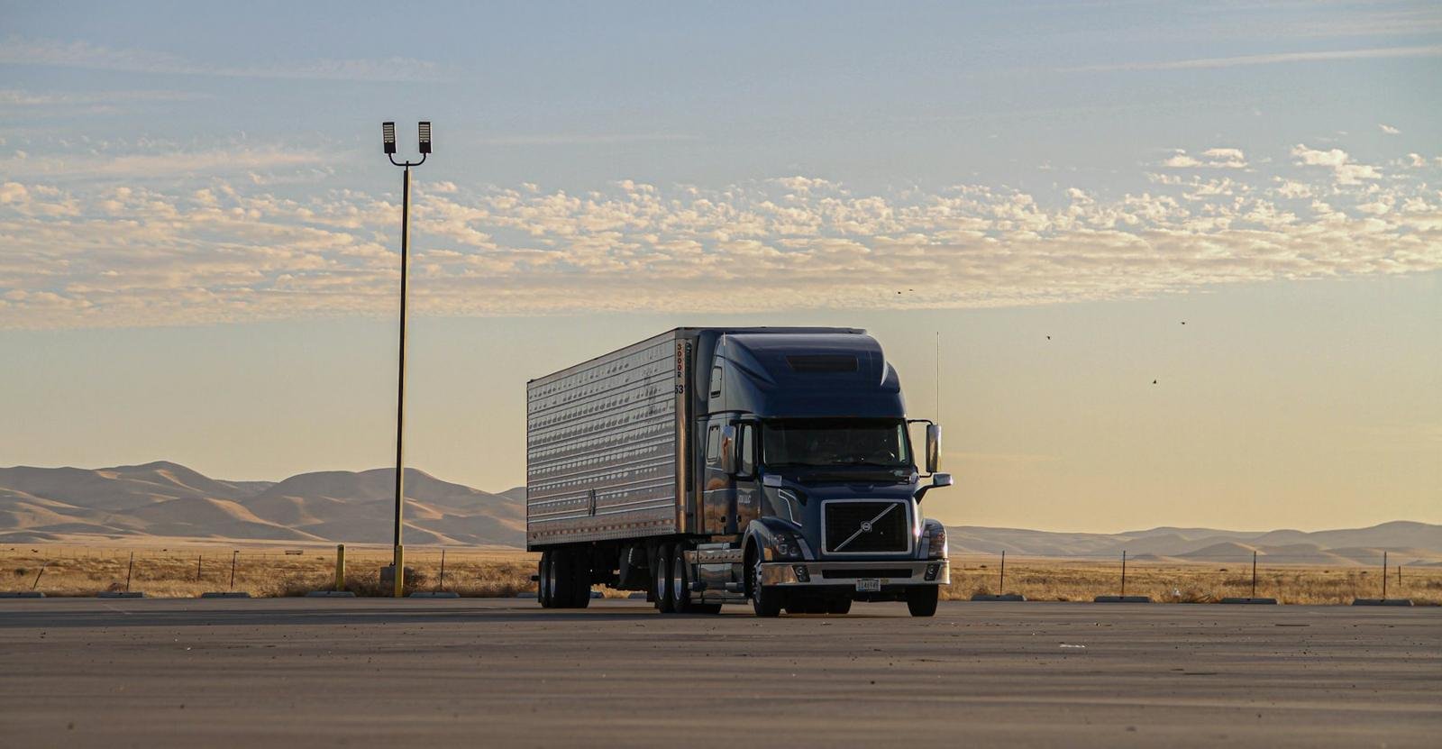 Tractor pulling a 53-foot dry van trailer on an open highway at sunset